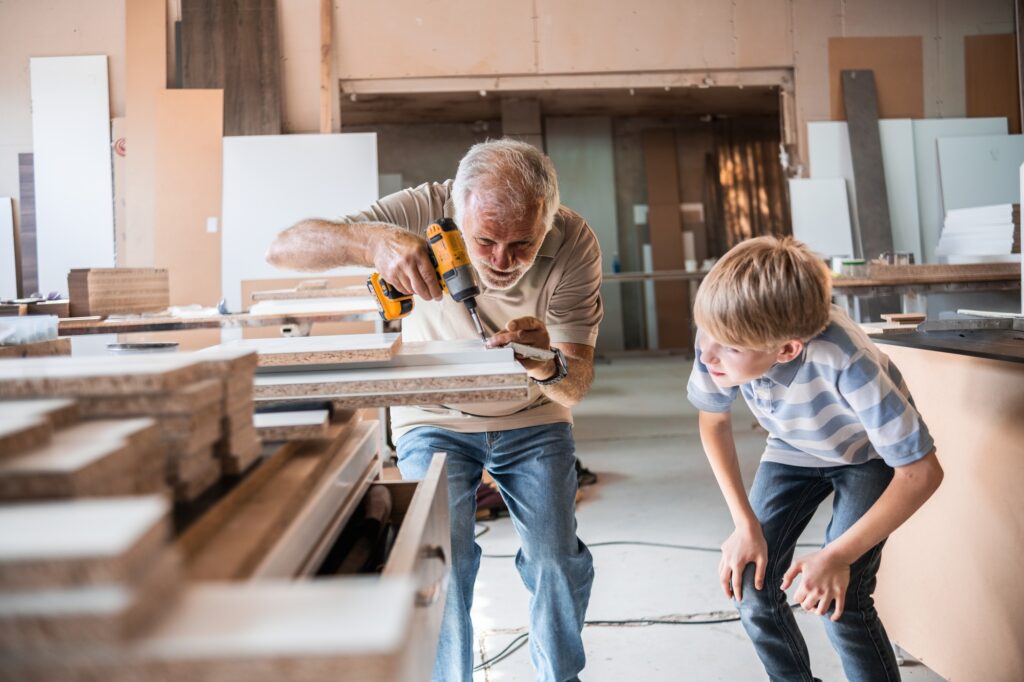 A grandfather teaches his grandson how to fix furniture